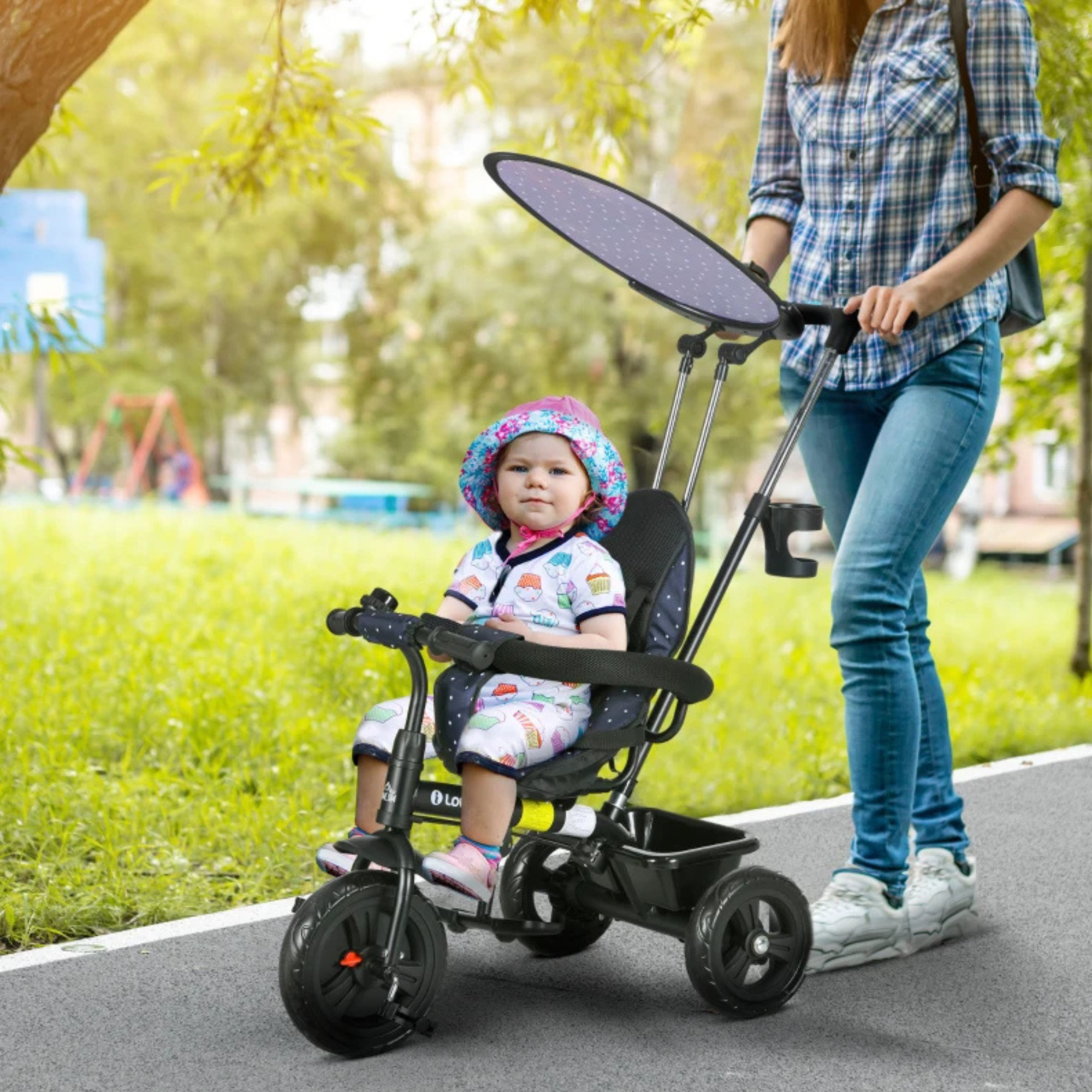 Kind op zittend op Driewieler voor kinderen van  1-5 jaar met duwstang, donkerblauw en stevig in park met ouder erbij